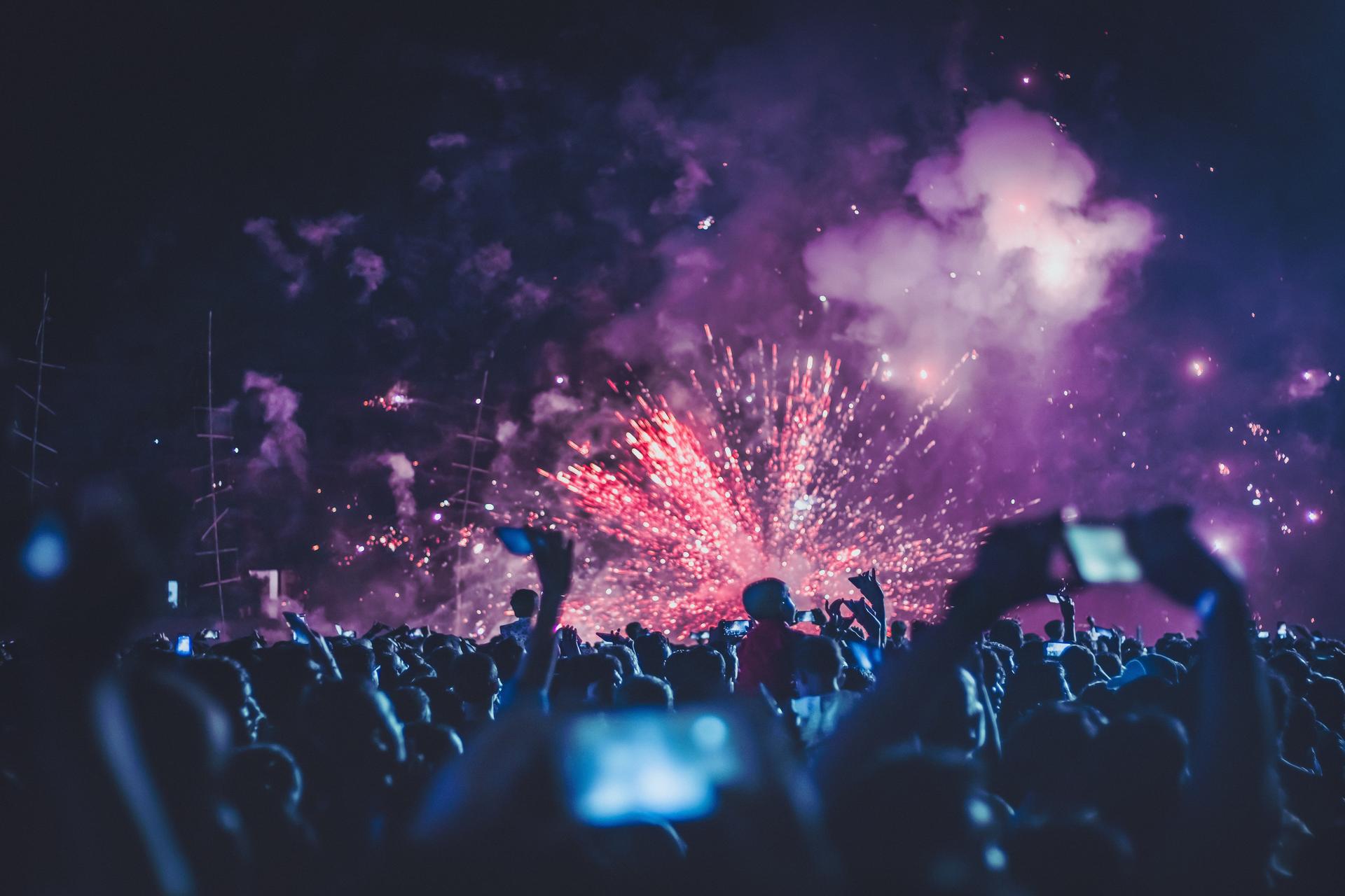 Festival crowd with fireworks and phones in the air